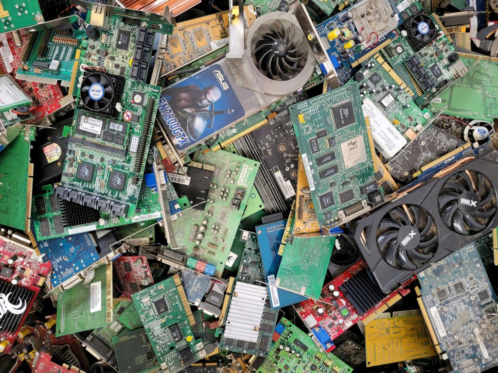 A collection of old computer electronics, including motherboards, computer fans, and circuit boards, ready for recycling to reduce electronic waste.